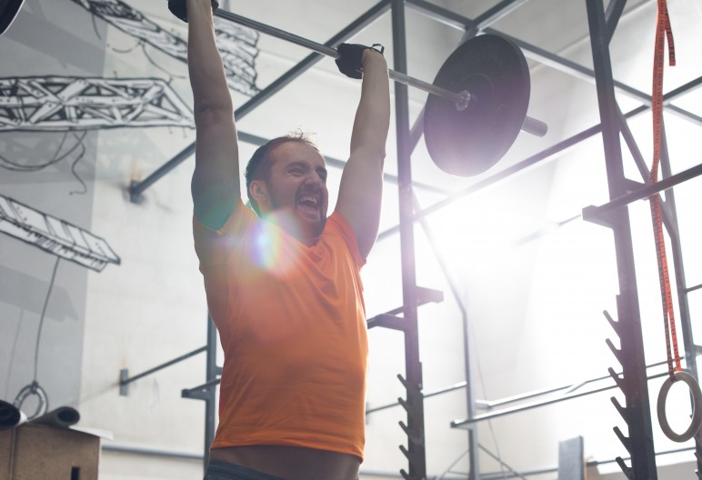 Dedicated man lifting barbell in crossfit gym